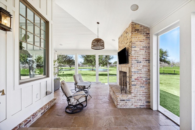 sunroom with lofted ceiling, plenty of natural light, and a fireplace