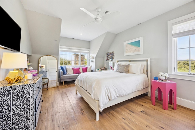 bedroom featuring arched walkways, hardwood / wood-style flooring, a ceiling fan, visible vents, and baseboards