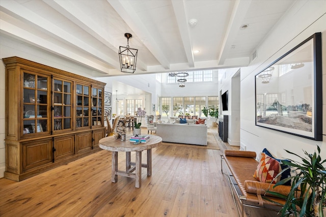 interior space featuring visible vents, beam ceiling, light wood-style flooring, and a notable chandelier