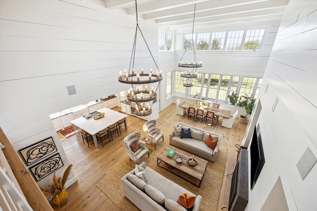 living area with a chandelier, beamed ceiling, wood walls, and wood finished floors