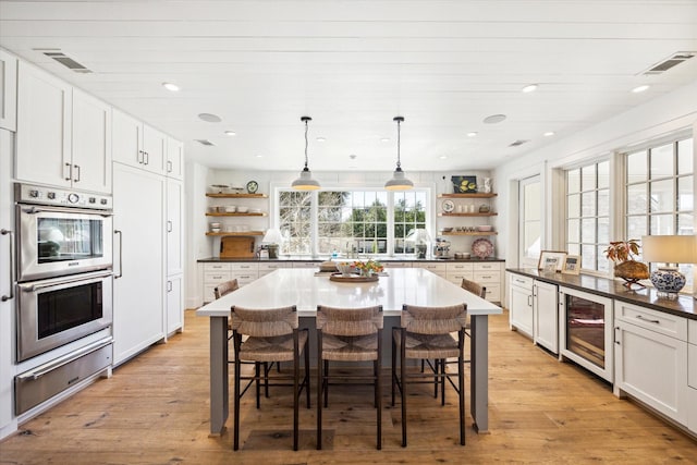 kitchen featuring a warming drawer, open shelves, wine cooler, and double oven