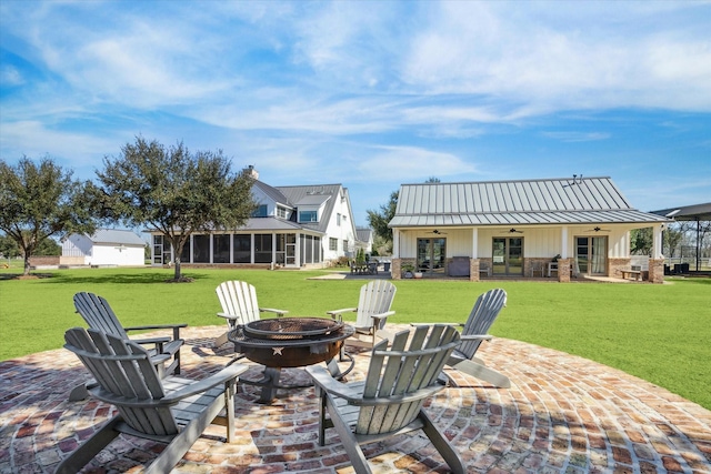 view of patio with a ceiling fan, an outdoor fire pit, and a sunroom