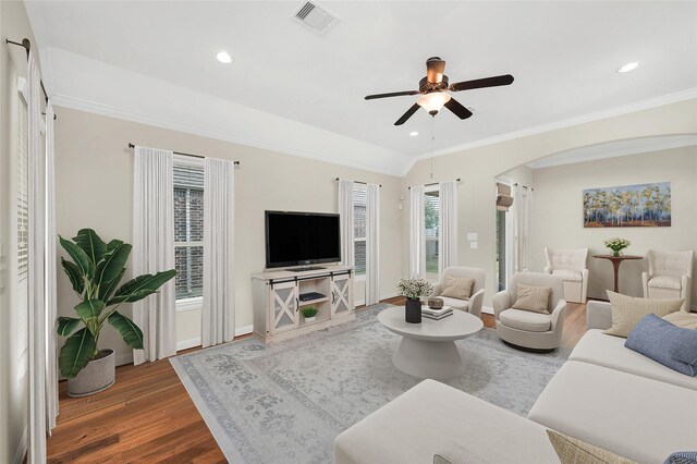 living area featuring arched walkways, visible vents, ceiling fan, and wood finished floors