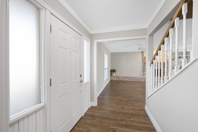 foyer entrance featuring dark wood-style flooring, ornamental molding, ceiling fan, a textured ceiling, and stairs