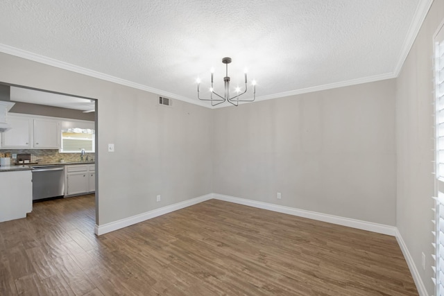 unfurnished dining area with crown molding, dark wood-style flooring, visible vents, and an inviting chandelier