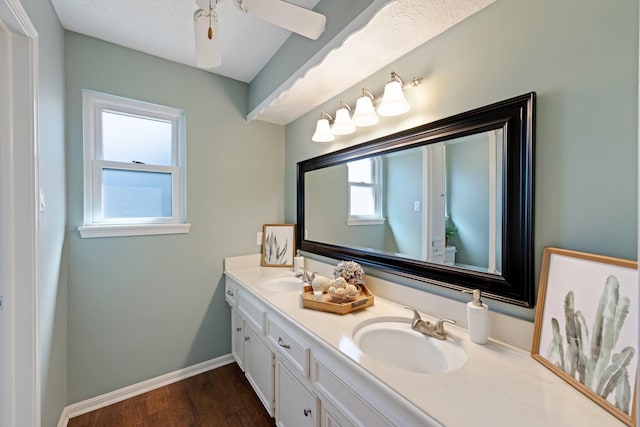 full bathroom with double vanity, baseboards, toilet, wood finished floors, and a sink