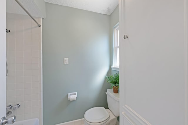 bathroom featuring shower / bath combination, toilet, and baseboards