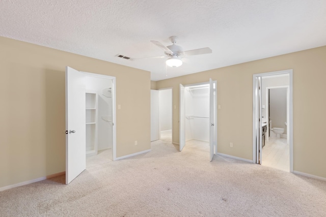 unfurnished bedroom featuring carpet floors, visible vents, a walk in closet, and a closet