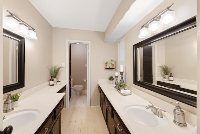 bathroom featuring toilet, two vanities, and a sink