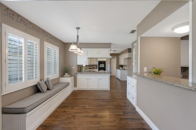 kitchen featuring dark wood-style flooring, visible vents, white cabinets, a textured ceiling, and a peninsula