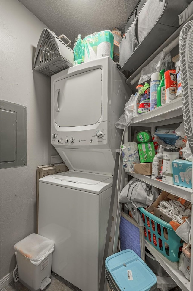 laundry room with laundry area, electric panel, stacked washer / dryer, and a textured ceiling