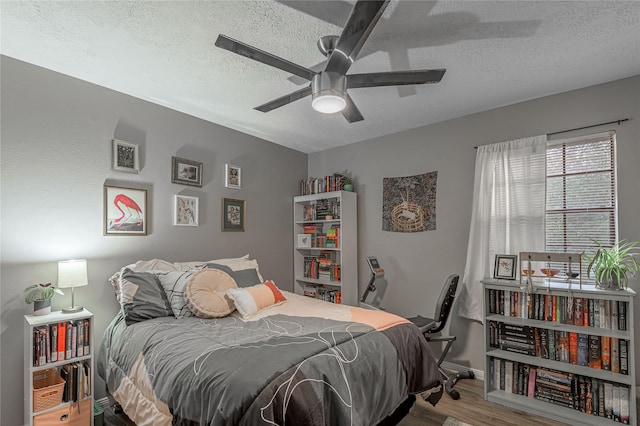 bedroom featuring ceiling fan, a textured ceiling, and wood finished floors