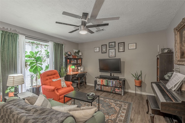 living room with baseboards, visible vents, a ceiling fan, wood finished floors, and a textured ceiling