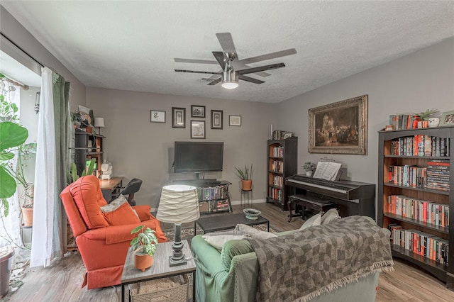 living area featuring a textured ceiling, a ceiling fan, and wood finished floors