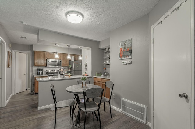 dining room featuring baseboards, a textured ceiling, visible vents, and dark wood-type flooring