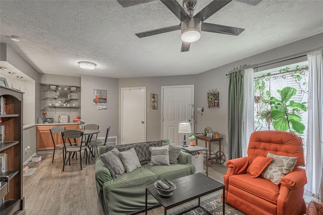 living area with light wood-style floors, a textured ceiling, and a ceiling fan