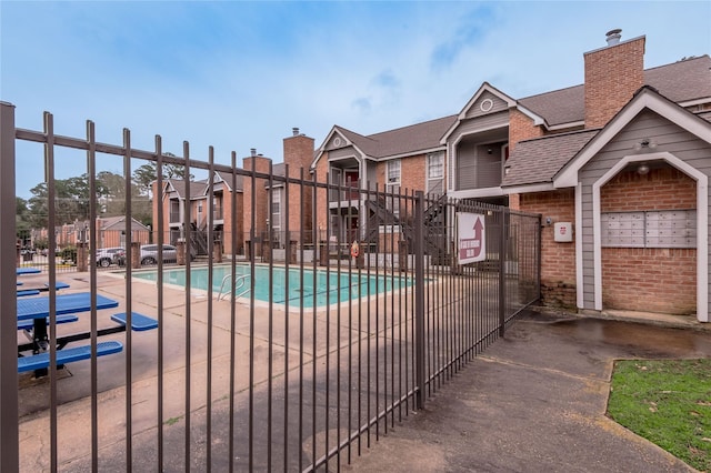 view of swimming pool featuring a residential view and fence