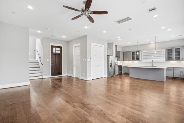 unfurnished living room featuring wood finished floors, a sink, visible vents, and recessed lighting