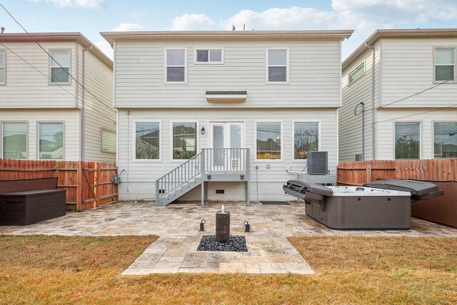 rear view of house featuring a patio area, a hot tub, a fenced backyard, and a yard