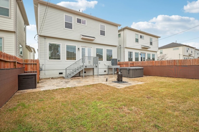 back of house featuring crawl space, a patio, a hot tub, and a lawn