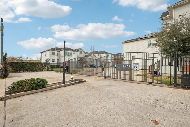 exterior space featuring a gate, a residential view, a gated entry, and curbs