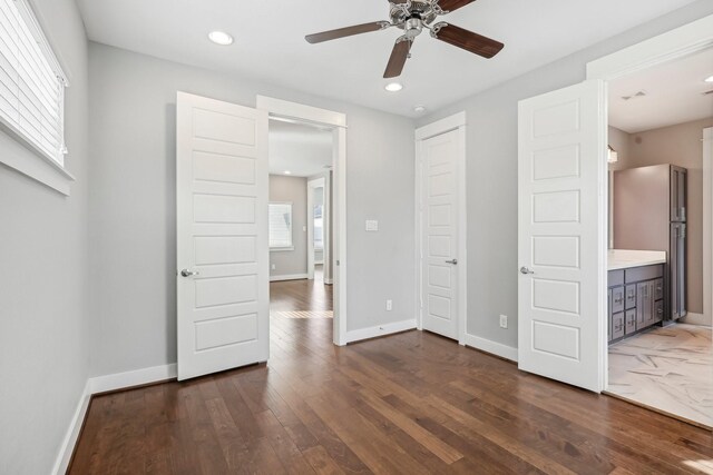 unfurnished bedroom with dark wood finished floors, freestanding refrigerator, and baseboards