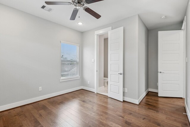 unfurnished bedroom featuring a ceiling fan, visible vents, baseboards, and wood finished floors