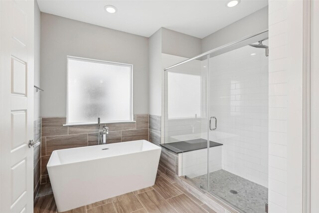 full bathroom featuring a stall shower, tile walls, a freestanding bath, and recessed lighting