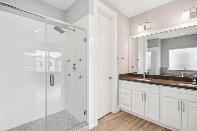 full bathroom with a stall shower, a sink, wood tiled floor, and double vanity