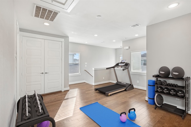 exercise area featuring baseboards, wood finished floors, visible vents, and recessed lighting