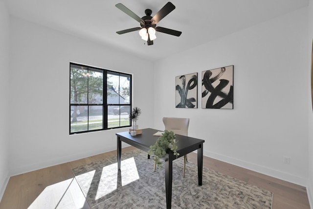 office featuring wood finished floors, a ceiling fan, and baseboards