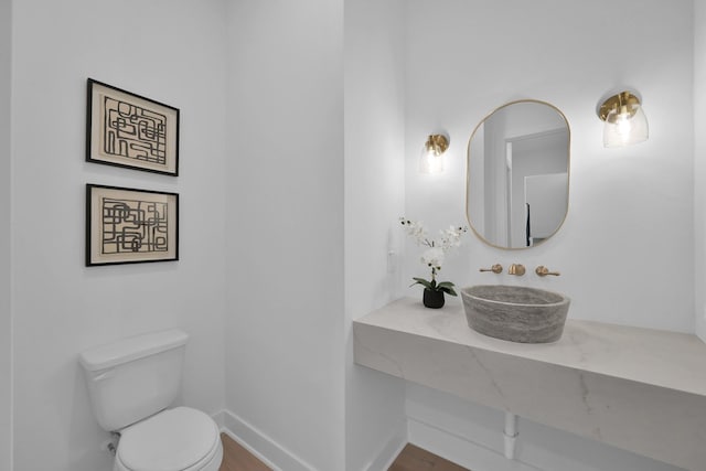 half bathroom with a sink, baseboards, and toilet