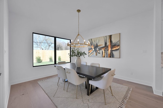 dining space with a notable chandelier, baseboards, and wood finished floors