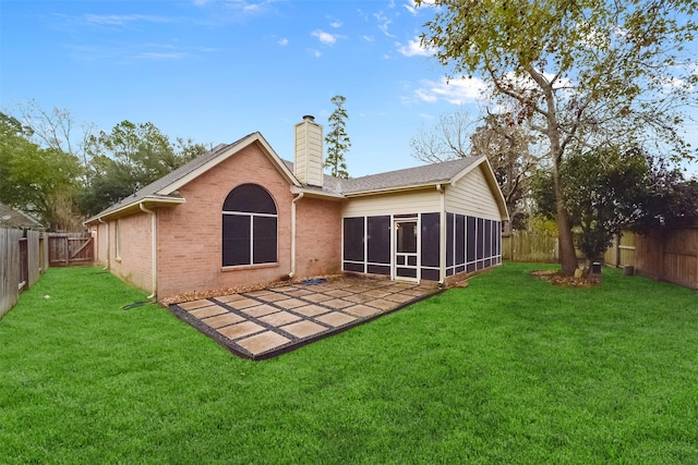 back of property with a fenced backyard, a chimney, a lawn, and brick siding