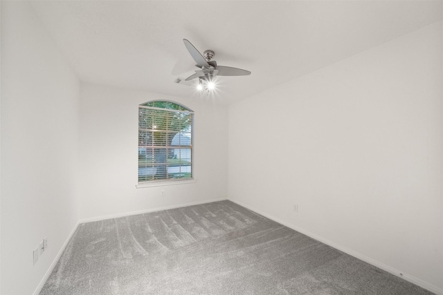 carpeted spare room featuring ceiling fan and baseboards