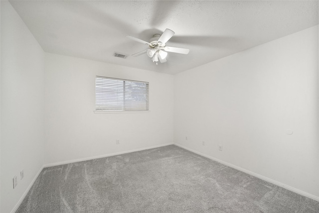 carpeted spare room featuring a ceiling fan, visible vents, a textured ceiling, and baseboards