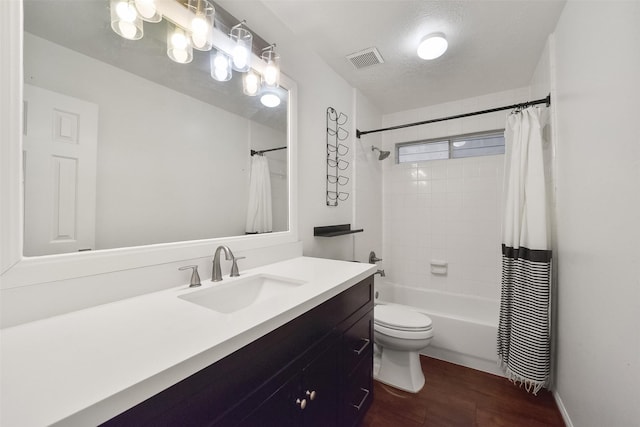 full bath featuring visible vents, toilet, shower / bath combo with shower curtain, a textured ceiling, and vanity