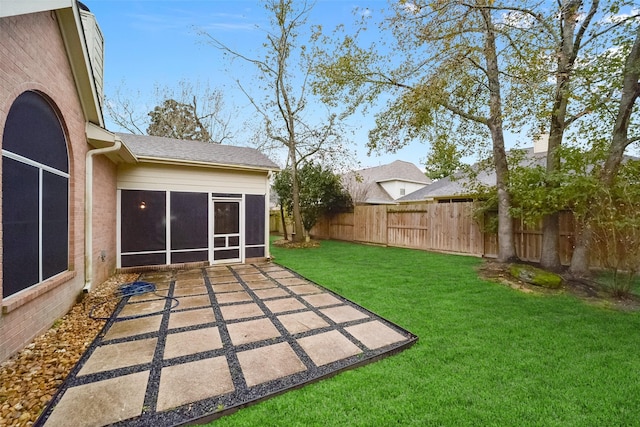 view of yard featuring a sunroom, a fenced backyard, and a patio area