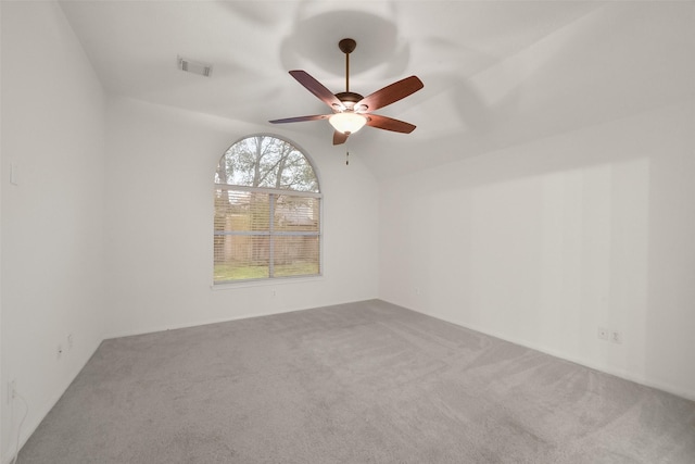 spare room featuring lofted ceiling, carpet, visible vents, and a ceiling fan