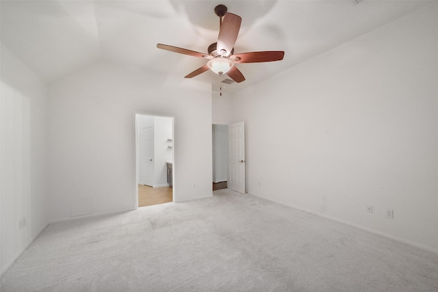 unfurnished bedroom with ceiling fan, vaulted ceiling, connected bathroom, and light colored carpet