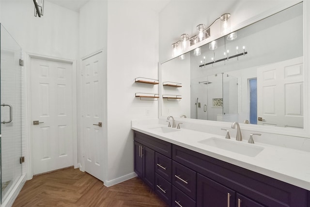 bathroom featuring double vanity, a stall shower, a sink, and baseboards