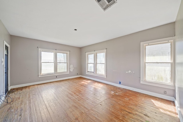 unfurnished room with wood-type flooring, visible vents, and baseboards