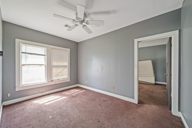 carpeted empty room with baseboards, visible vents, and ceiling fan