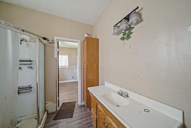 full bathroom featuring a shower stall, baseboards, wood finished floors, and vanity