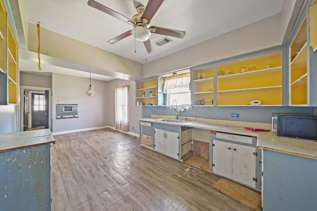 kitchen featuring black microwave, wood finished floors, a sink, visible vents, and open shelves