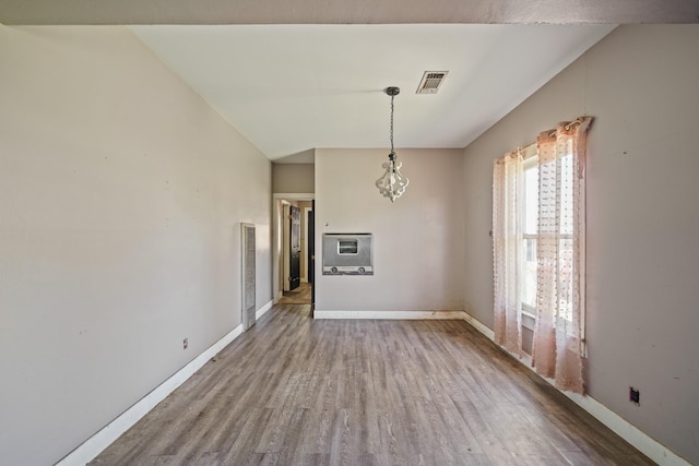 unfurnished dining area with heating unit, visible vents, vaulted ceiling, wood finished floors, and baseboards