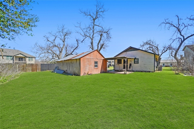 rear view of house with an outbuilding, a yard, a patio, and a fenced backyard