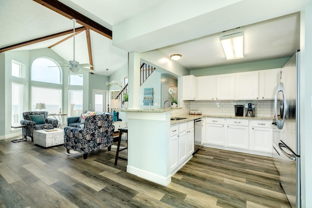 kitchen with tasteful backsplash, light stone counters, appliances with stainless steel finishes, open floor plan, and a sink