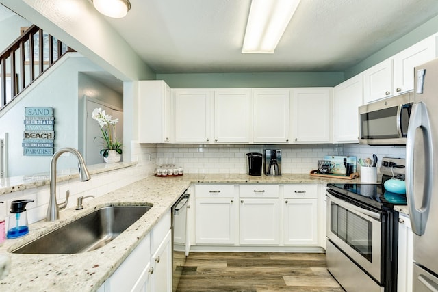 kitchen with white cabinetry, appliances with stainless steel finishes, a sink, and wood finished floors