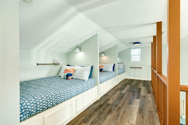 bedroom with a textured ceiling, vaulted ceiling, wood finished floors, and baseboards